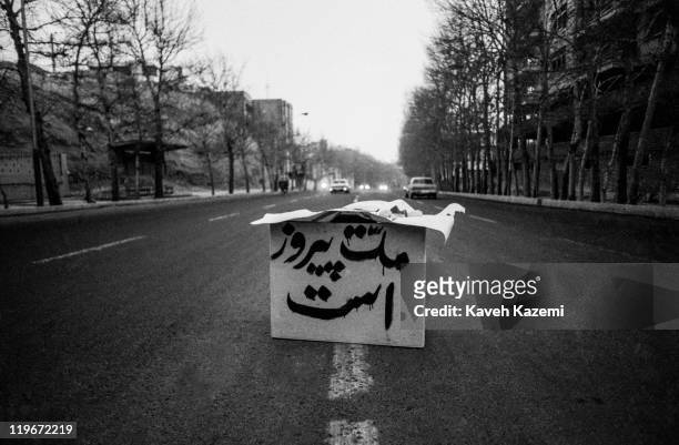An empty box with the slogan 'Nation is Victorious' is placed in the middle of Pahlavi Avenue at dusk after the victory of the Islamic revolution in...
