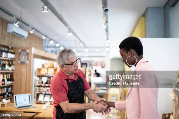 saler welcoming a customer to a store - entering shop stock pictures, royalty-free photos & images