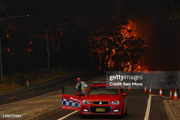 New South Wales Police officer prepares to flee his roadblock on the Princes Highway near the town of Sussex Inlet on December 31, 2019 in Sydney,...