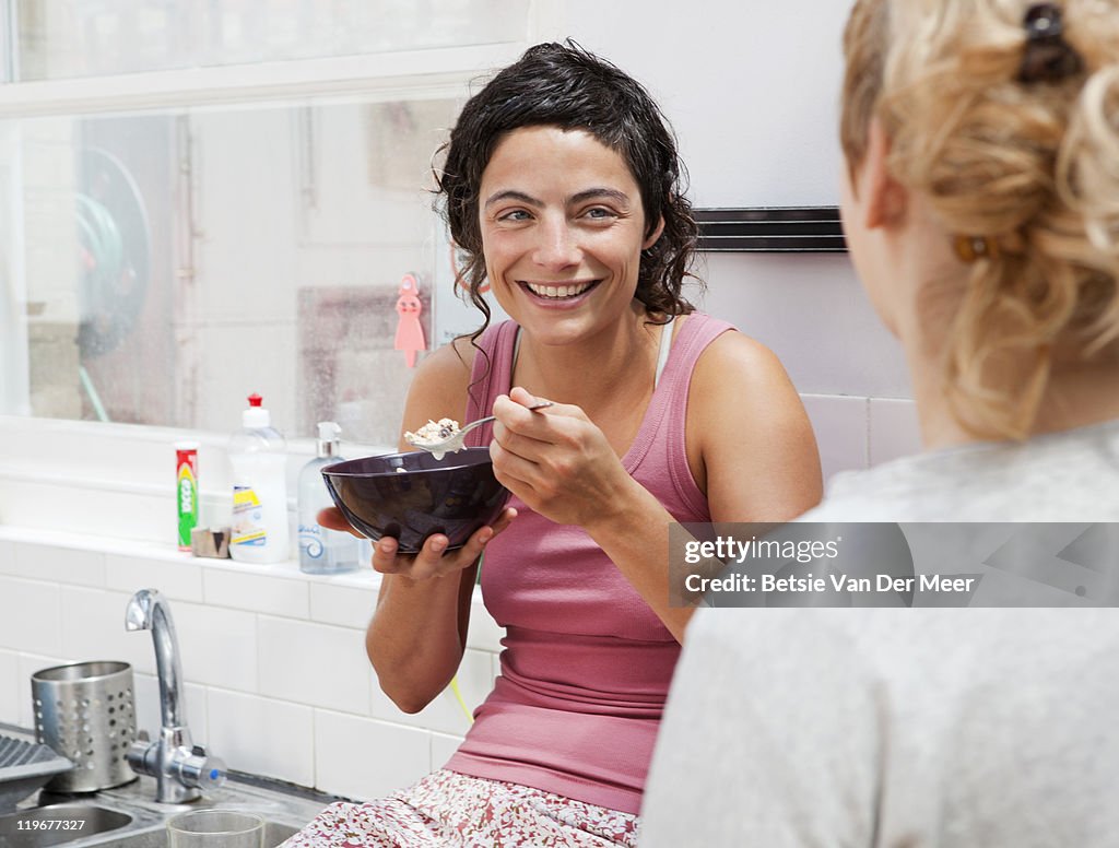 Woman laughing at friend while having breakfast.