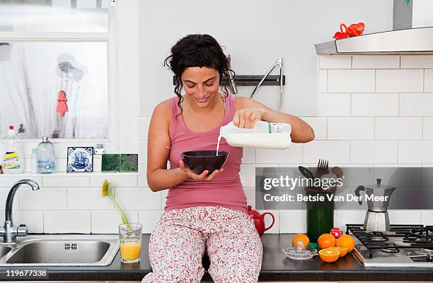 woman pouring milk on cereal in kitchen. - milk pour - fotografias e filmes do acervo