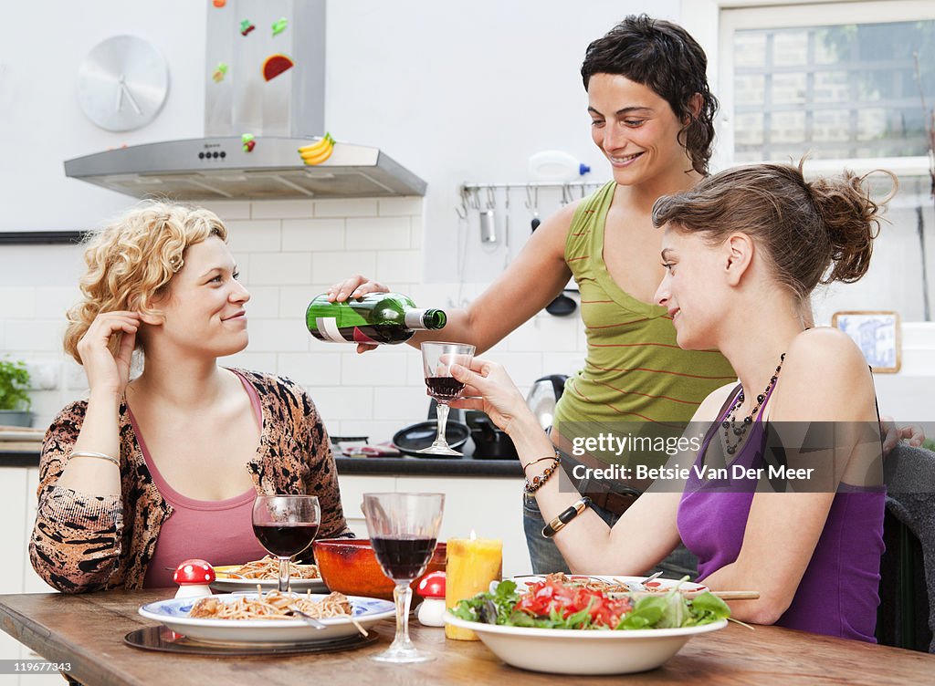 Woman pours wine into friends glass.