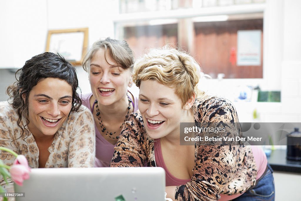 Woman laughing, while looking at laptop.