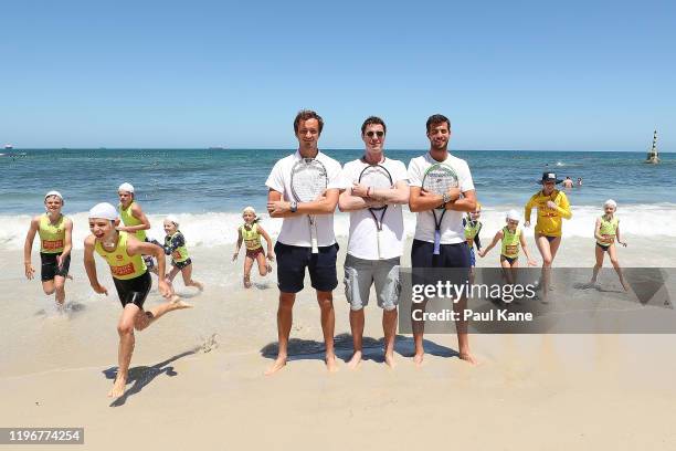 Daniil Medvedev, Marat Safin and Karen Khachanov of Russia pose as Surf Life Saving nippers run from the water ahead of the 2020 ATP Cup Group Stage...