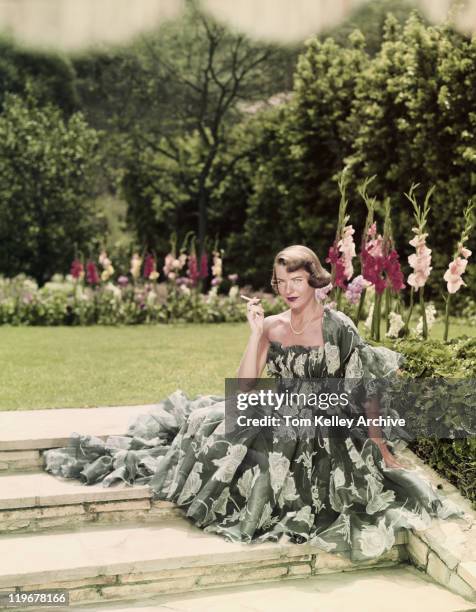 young woman smoking cigarette in garden, portrait - beautiful women smoking cigarettes stock pictures, royalty-free photos & images