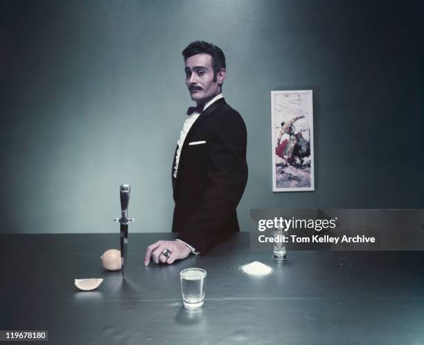 magician standing by table with glass of water, salt and knife - magician stock pictures, royalty-free photos & images