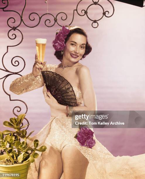 joven mujer sosteniendo vaso de cerveza con abanico plegable, sonriendo, portra - 1950 1959 fotografías e imágenes de stock