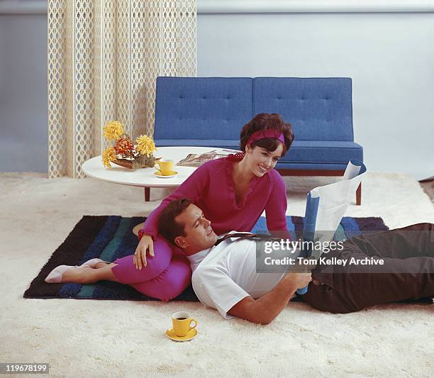 couple looking at blueprint in living room, smiling - 1950 1959 stockfoto's en -beelden
