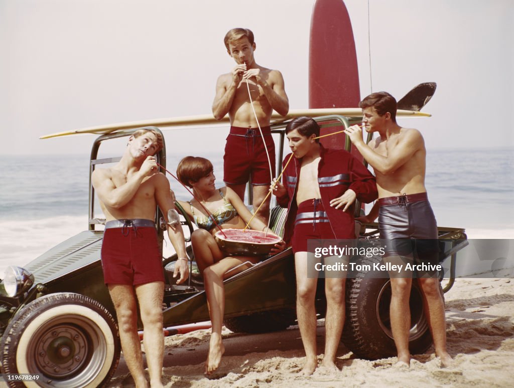 Friends drinking juice from watermelon on beach