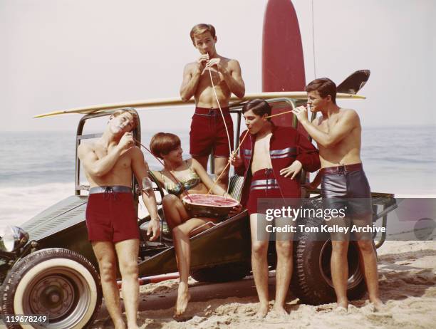 friends drinking juice from watermelon on beach - archival beach stock pictures, royalty-free photos & images