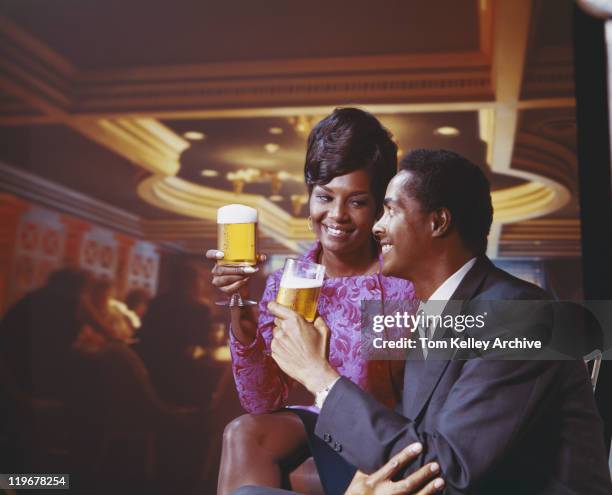 young couple holding glass of beer, smiling  - archival 1960s stock pictures, royalty-free photos & images