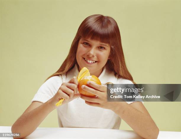 teenager mädchen peeling orange, lächeln, porträt - 1975 stock-fotos und bilder