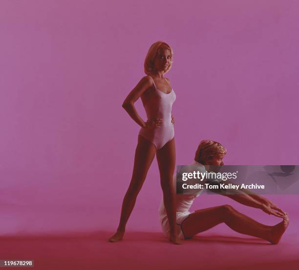 frau und mann stretching auf rosa hintergrund - 1975 stock-fotos und bilder