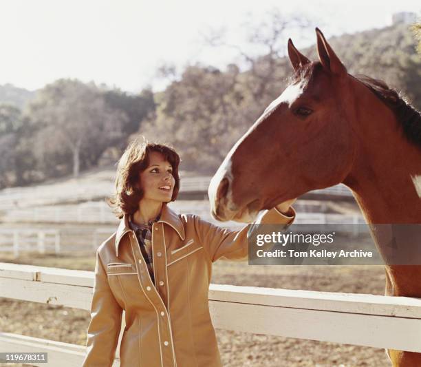 mulher stroking cavalo ao lado do muro - 1975 - fotografias e filmes do acervo