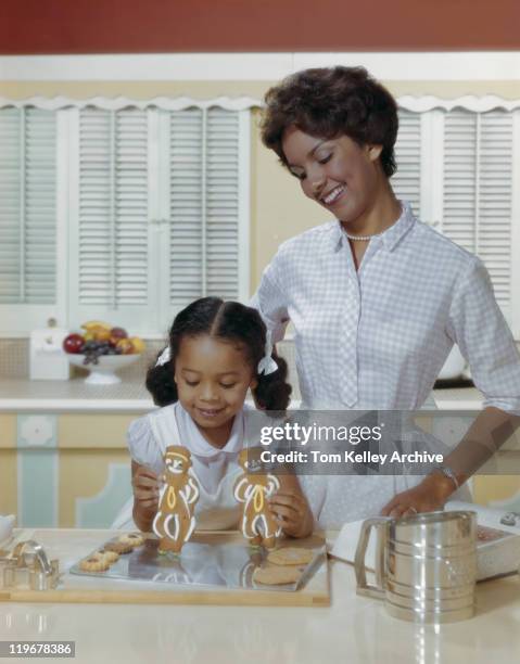 mother and daughter with gingerbread biscuits, smiling - 1960 kitchen stock pictures, royalty-free photos & images