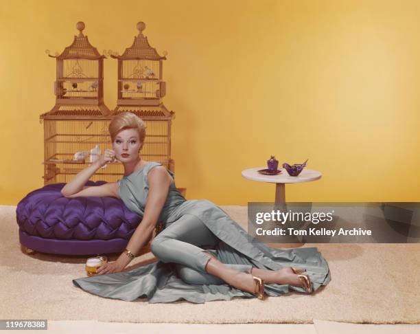 young women lying and holding beer glass while birdcage in background - 1960s stock pictures, royalty-free photos & images