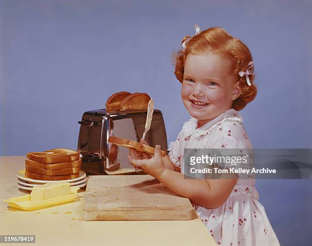 girl spreading butter on toast, smiling, portrait - butter knife stock pictures, royalty-free photos & images