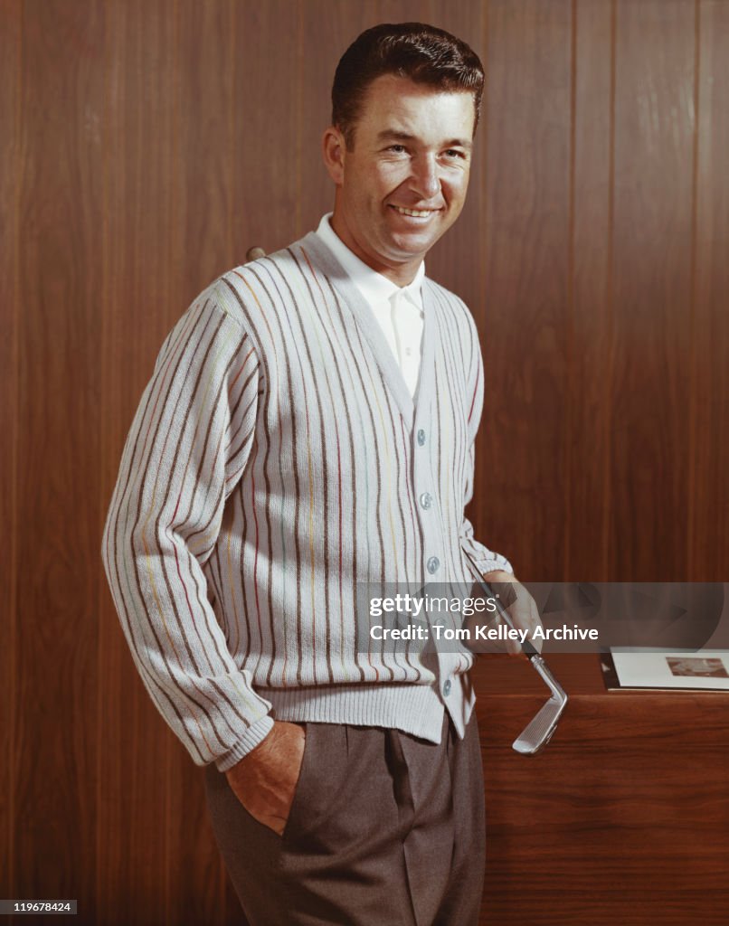 Man holding golf club, smiling