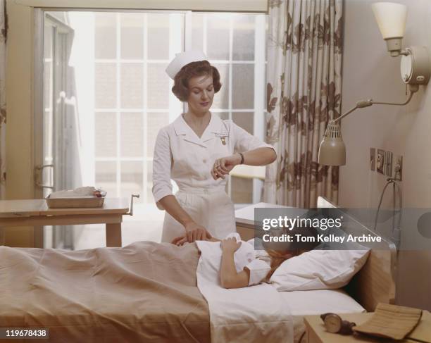 female nurse checking pulse of girl in bed - 1960 stock pictures, royalty-free photos & images