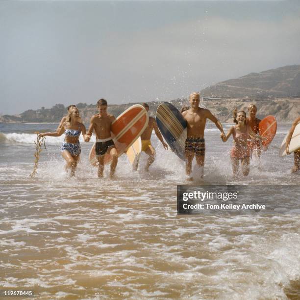 group of surfers running in water with surfboards, smiling - 1960 個照片及圖片檔