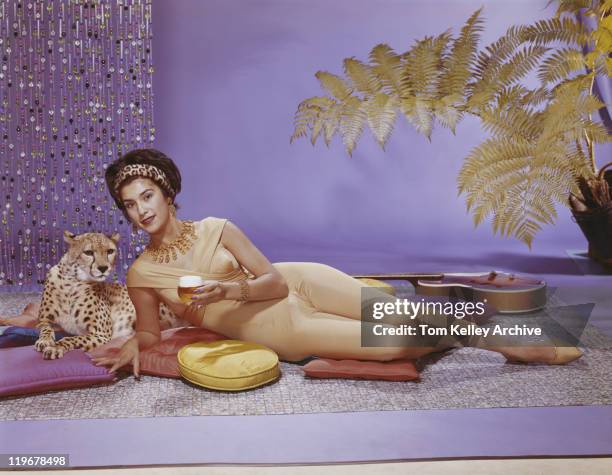 young woman lying on cushion with leopard - cat with collar stockfoto's en -beelden