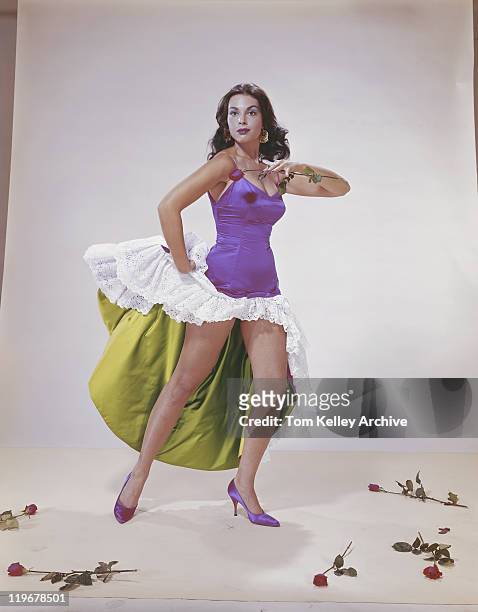 young woman holding rose and dancing while roses on floor - 1962 fotografías e imágenes de stock