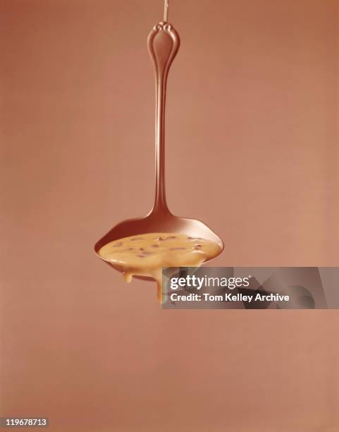 sauce dripping from ladle against brown background - ladle stock pictures, royalty-free photos & images