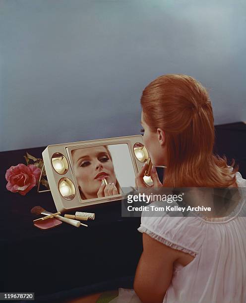 young woman applying lipstick - 1960s woman stock pictures, royalty-free photos & images