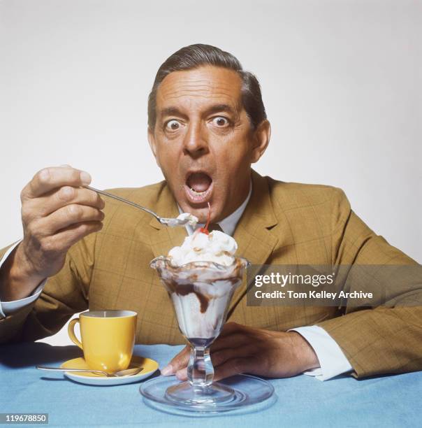 mature man eating sundae against white background, close-up - man with spoon in mouth stock pictures, royalty-free photos & images