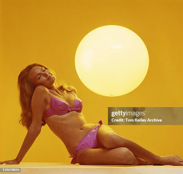 young woman with eyes closed and sun in background - swimwear stockfoto's en -beelden