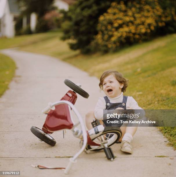 girl llanto junto a triciclo - triciclo fotografías e imágenes de stock