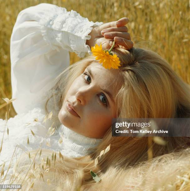 junge frau liegen in der wiese holding blume, porträt - 1970's long hair stock-fotos und bilder