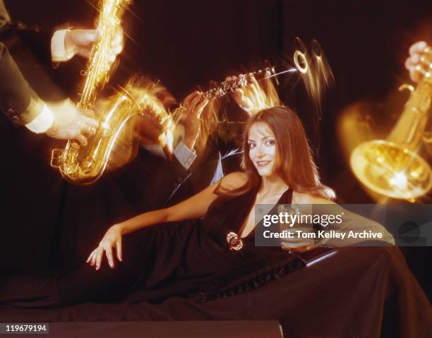 young woman in black dress holding drink and surrounded by musician - 1973 stock pictures, royalty-free photos & images