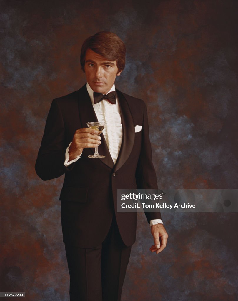 Man in suit and bow tie holding drink, portrait