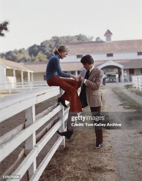 woman sitting on fence and holding hands of man - 1973 stockfoto's en -beelden