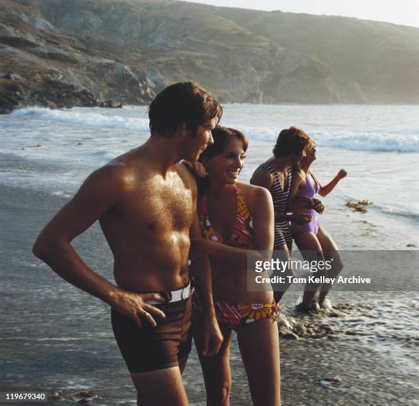 pareja joven parado en playa sonriendo - de archivo fotografías e imágenes de stock
