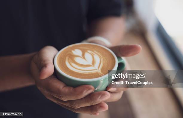 coffee cup latte art. hands holding cup of hot coffee latte cappuccino. giving with love and take care concept. good service coffee shop. - coffee art stock pictures, royalty-free photos & images