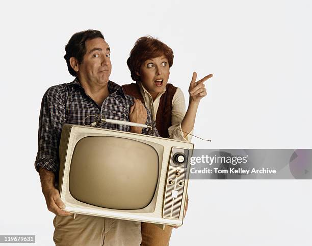 couple with facial expression holding old television - 1982 stock pictures, royalty-free photos & images