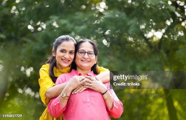 frau umarmt mutter im park - indian mother daughter stock-fotos und bilder