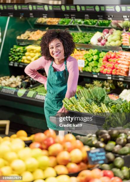 jeune femme afro-américaine travaillant dans l'épicerie - rayon fruits et légumes photos et images de collection