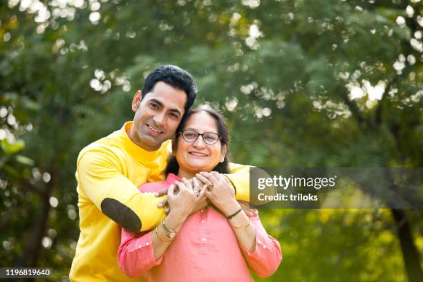 man embracing mother at park - indian mother and son stock pictures, royalty-free photos & images