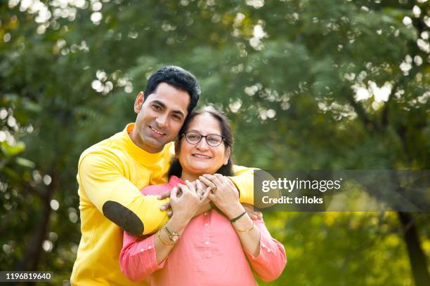 man embracing mother at park - indian mother stock pictures, royalty-free photos & images