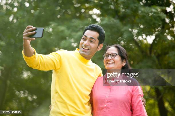 happy man taking selfie with his mother at park - mother and son stock pictures, royalty-free photos & images