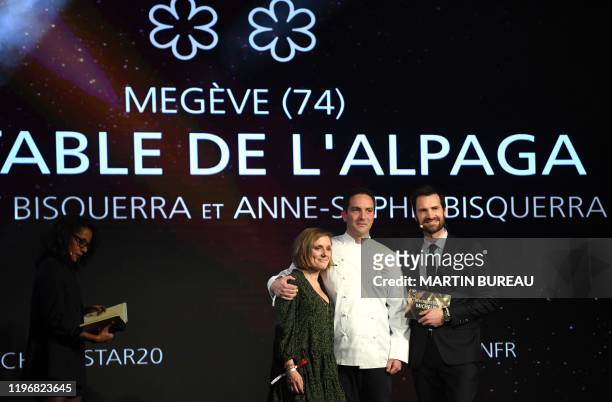 Michelin guide international director Gwendal Poullennec stands on stage next to chef Anthony Bisquerra and his wife Anne-Sophie of restaurant Table...