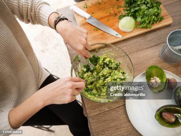 giovane donna che fa guacamole - preparazione foto e immagini stock