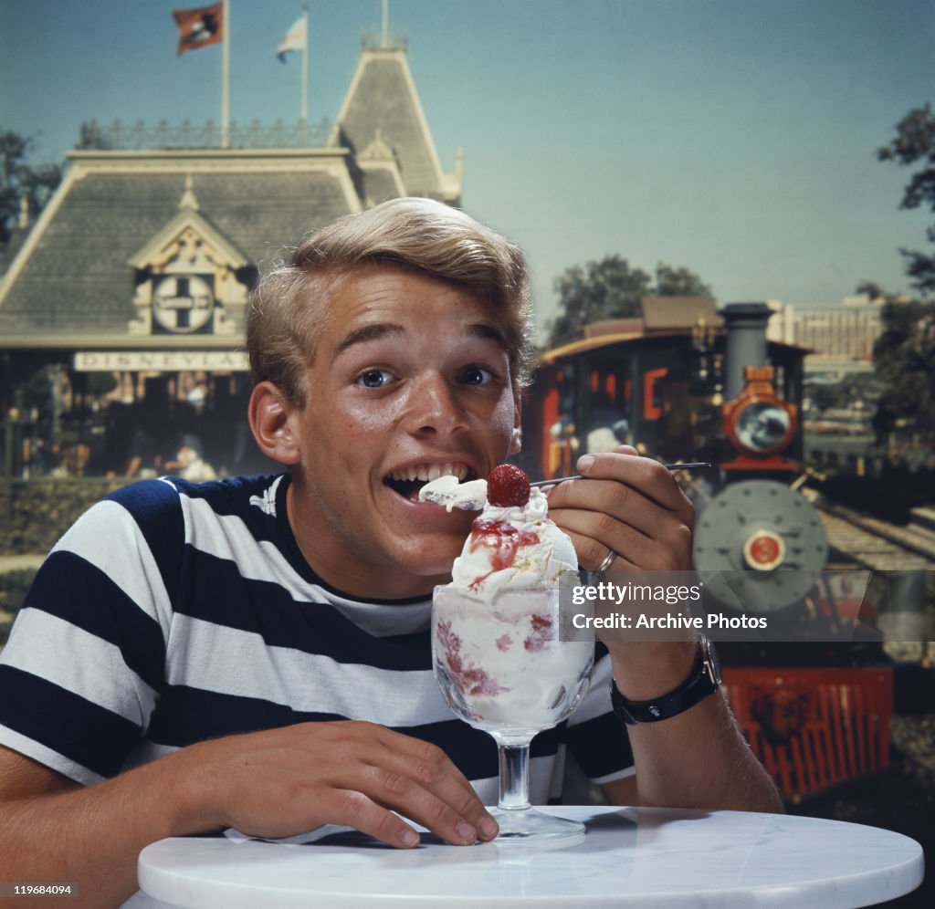 Young man eating ice cream, smiling, portrait