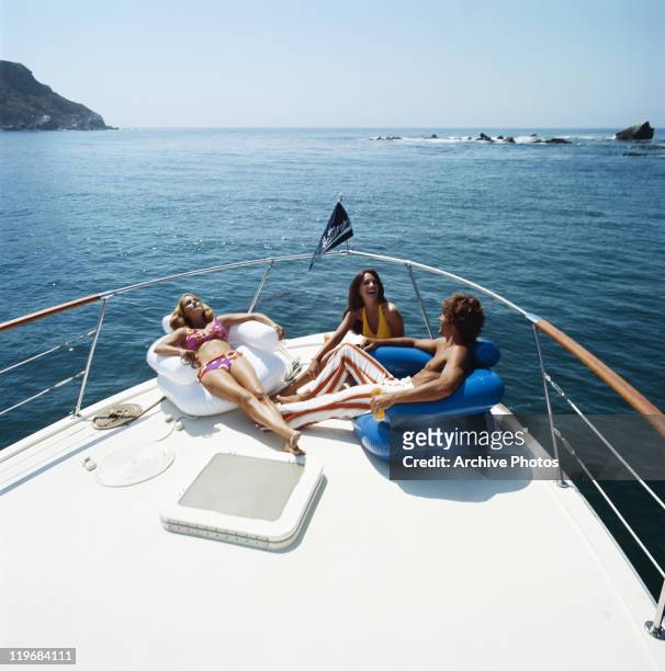 Young women and men resting on sailing boat, smiling