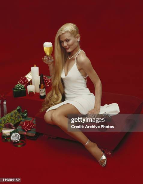 Young woman holding beer glass, smiling, portrait