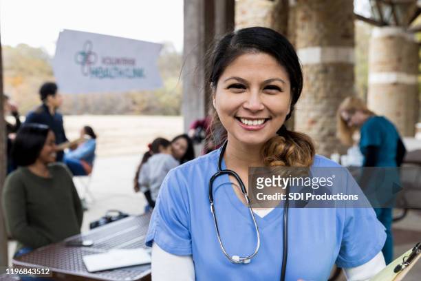 portrait mid adult female volunteer doctor at free clinic - medical building exterior stock pictures, royalty-free photos & images