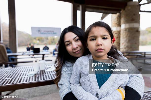 mother holds nervous daughter in her lap at free clinic - family sadness stock pictures, royalty-free photos & images